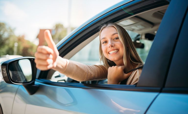 Young woman in car giving thumbs up
